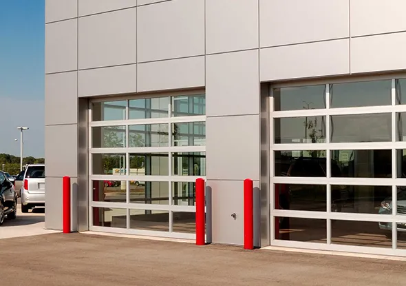 Modern commercial facility in Portage, Indiana with large glass garage doors and red safety bollards.