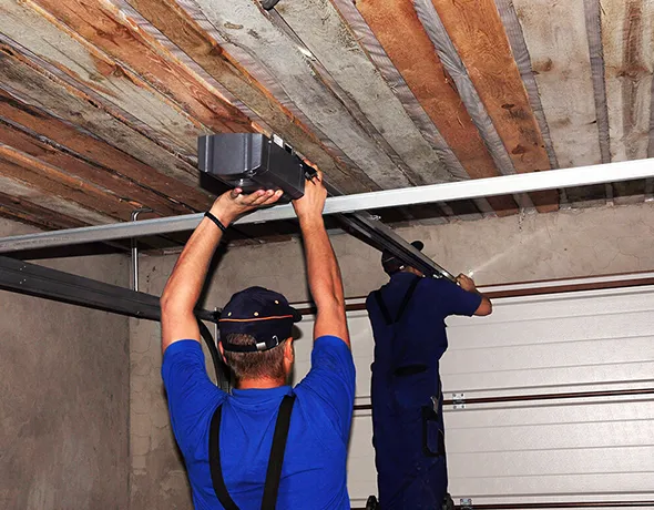 Technician installing or repairing garage door opener from below wooden ceiling.